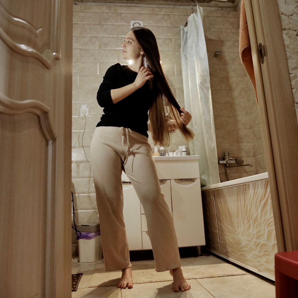 Woman brushing her hair in a bathroom.